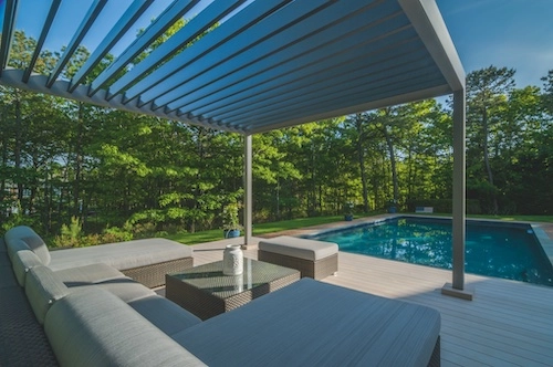 Bioklimatická pergola Renson od PLAS.cz s pohyblivými lamelami, která nabízí luxusní odpočinkové posezení u bazénu v přírodním prostředí.
