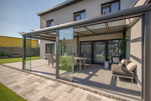 Nezateplená prosklená pergola od PLAS.cz, která rozšiřuje obytný prostor domu a poskytuje stylové venkovní posezení s ochranou proti větru.