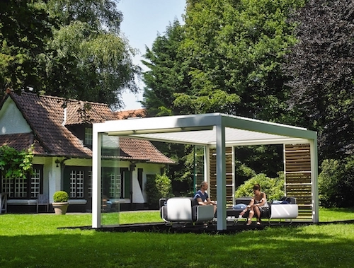 Moderní bioklimatická pergola Renson od PLAS.cz s elegantním bílým rámem a skleněnými stěnami, která vytváří luxusní venkovní posezení v zahradě.