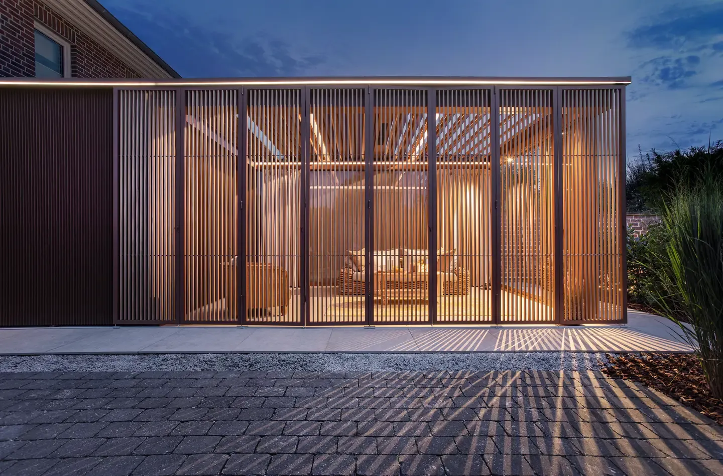 Bioklimatická pergola Renson od PLAS.cz s pohyblivými lamelami, která nabízí luxusní odpočinkové posezení u bazénu v přírodním prostředí.