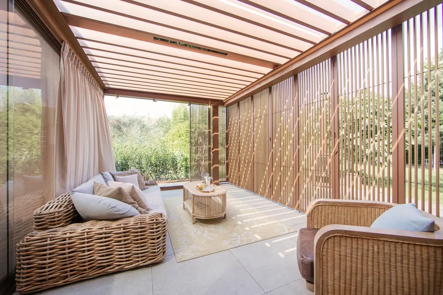 Moderní bioklimatická pergola Renson od PLAS.cz s elegantním bílým rámem a skleněnými stěnami, která vytváří luxusní venkovní posezení v zahradě.