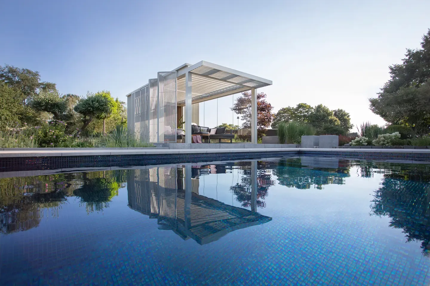 Moderní hliníková pergola Renson od PLAS.cz sloužící jako elegantní přístřešek pro automobil, ktrerý dokonale ladí s architekturou domu.