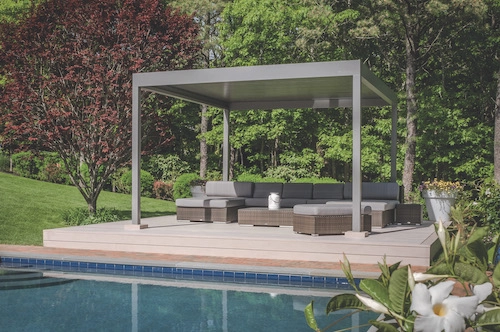 Bioklimatická pergola Renson od PLAS.cz umístěná u bazénu, která poskytuje elegantní stíněné posezení v přírodním prostředí.