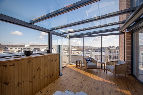 Nezateplená prosklená pergola od PLAS.cz na střešní terase s panoramatickým výhledem, která vytváří stylový prostor pro relaxaci.