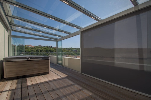 Nezateplená prosklená pergola od PLAS.cz na střešní terase s vířivkou a panoramatickým výhledem do krajiny.
